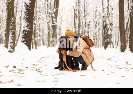 Woman with adorable Labrador Retriever dog in snowy park Stock Photo