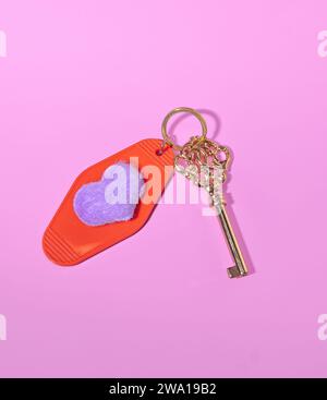 A Gold Skeleton Key with a Heart Shaped Hotel Room Tag, Key to Love Concept, Keys to My Heart, Valentine's Day on a Pink Background Stock Photo