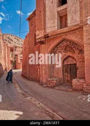 Local woman in traditional clothing walks in a narrow street in the historical village of Abyaneh, Natanz County, Iran. Stock Photo