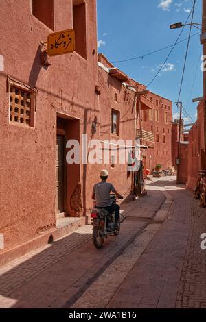 Man on a motorbike rides in a narrow street in the historical village of Abyaneh, Natanz County, Iran. Stock Photo