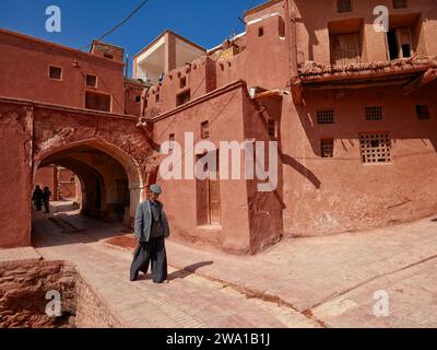 Local man in traditional clothing walks in a narrow street in the historical village of Abyaneh, Natanz County, Iran. Stock Photo