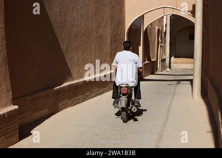 Man on a motorbike rides in a narrow alley in the historic center of Kashan, Iran. Stock Photo