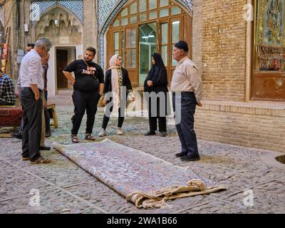 Sellers talk with their customers finalizing sale of an expensive Persian carpet in the Grand Bazaar of Kashan, Iran. Stock Photo