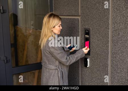 Middle aged woman pushing button of intercom Stock Photo