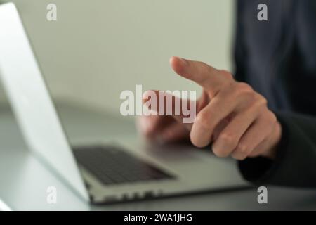 Finger pointing to laptop screen with important technology news. Businessman pressing virtual button on display. Stock Photo
