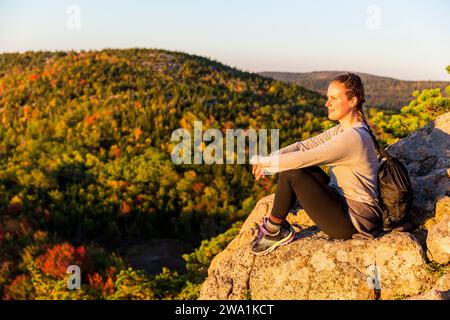 Young woman enjoying view from trail on Beehive in fall in Acadia National Park, Maine, USA Stock Photo