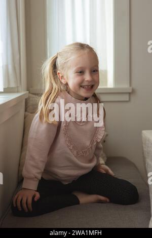 Young girl laughs happily during family breakfast in kitchen Stock Photo