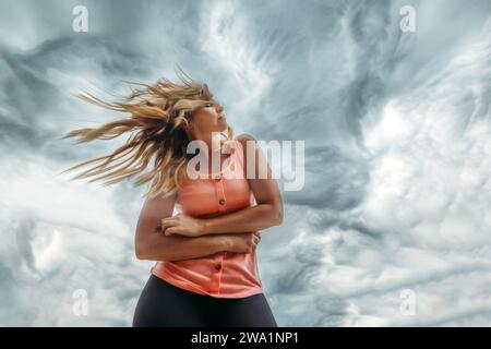 Woman standing in the wind with storm clouds behind her Stock Photo