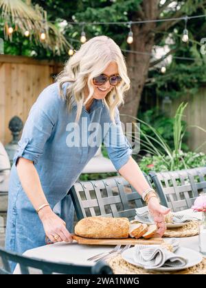 Loving mother setting the table for an outdoor family dinner Stock Photo