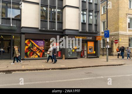 People walking past a Sainsbury’s Local store on St Andrew’s Street in Cambridge, April 2023. Stock Photo