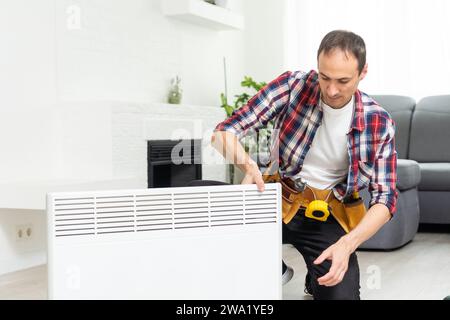 Workman mounting water heating radiator near the window in the white renovated living room, Image with copy space Stock Photo