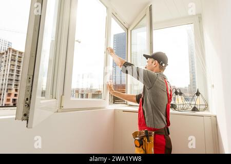 Worker man installs plastic windows and doors with double-glazed white. Stock Photo