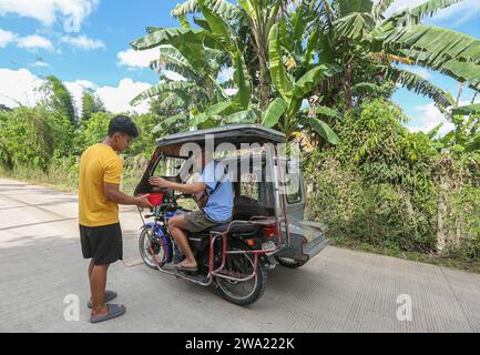 Tiaong, Philippines. 1st Jan 2024: In rural provinces, Filipino poor families setting up friendly toll roads with a rope and a Happy New Year sign. Cars, tricycles or pedestrians are encouraged to make 'thanks giving' donations, generally only a few pesos, without obligation, always with smile and sometimes embellished with few dance steps. A tradition that was practiced only in certain regions and which has spread to almost the entire country since the COVID 19 epidemic hard days. As example, over 1 km, in certain places you can count up to fifteen stops. Credit: Kevin Izorce/Alamy Live News Stock Photo