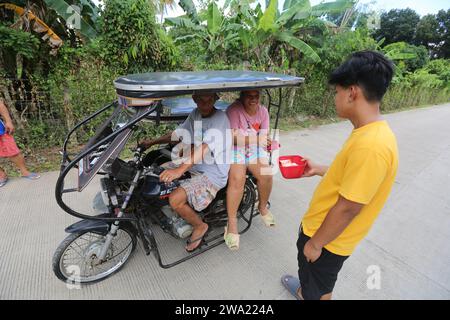 Tiaong, Philippines. 1st Jan 2024: In rural provinces, Filipino poor families setting up friendly toll roads with a rope and a Happy New Year sign. Cars, tricycles or pedestrians are encouraged to make 'thanks giving' donations, generally only a few pesos, without obligation, always with smile and sometimes embellished with few dance steps. A tradition that was practiced only in certain regions and which has spread to almost the entire country since the COVID 19 epidemic hard days. As example, over 1 km, in certain places you can count up to fifteen stops. Credit: Kevin Izorce/Alamy Live News Stock Photo