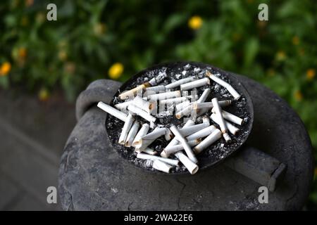 An ashtray for cigarette butts on the street. Smoked cigarettes in the trash. Stock Photo