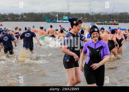 Haltern, Germany. 01st Jan, 2024. Participants brave the cold water. A record 590 registered swimmers, the highest number in many years, plus visitors, have fun at the annual New Year's Day swim, an open water swimming event which takes place at Haltern Lake in the town of Haltern, North Rhine Westphalia. Despite unpredictable weather with rain, many brave the run along the beach and into the cold lake in costumes to celebrate the new year in style. All proceeds of the event go to local charities. Credit: Imageplotter/Alamy Live News Stock Photo