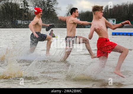 Haltern, Germany. 01st Jan, 2024. Participants brave the cold water. A record 590 registered swimmers, the highest number in many years, plus visitors, have fun at the annual New Year's Day swim, an open water swimming event which takes place at Haltern Lake in the town of Haltern, North Rhine Westphalia. Despite unpredictable weather with rain, many brave the run along the beach and into the cold lake in costumes to celebrate the new year in style. All proceeds of the event go to local charities. Credit: Imageplotter/Alamy Live News Stock Photo