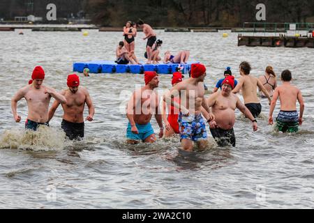 Haltern, Germany. 01st Jan, 2024. Participants brave the cold water. A record 590 registered swimmers, the highest number in many years, plus visitors, have fun at the annual New Year's Day swim, an open water swimming event which takes place at Haltern Lake in the town of Haltern, North Rhine Westphalia. Despite unpredictable weather with rain, many brave the run along the beach and into the cold lake in costumes to celebrate the new year in style. All proceeds of the event go to local charities. Credit: Imageplotter/Alamy Live News Stock Photo