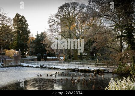 UK, England, Cheshire, Macclesfield, Gawsworth, St James’ church across frozen pond in winter Stock Photo