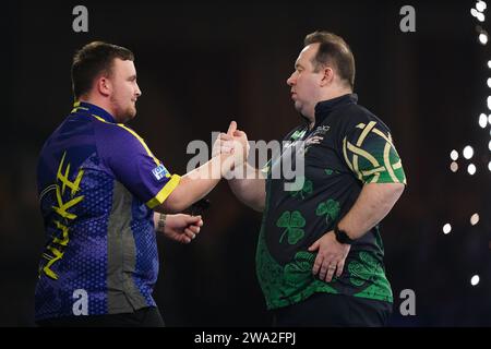 Luke Littler celebrates victory over Brendan Dolan (right) on day fourteen of the Paddy Power World Darts Championship at Alexandra Palace, London. Picture date: Monday January 1, 2024. Stock Photo