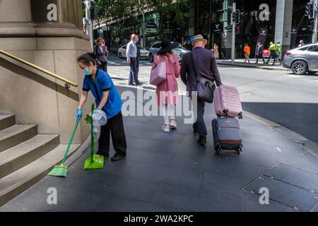 A hotel worker sweeping the steps of the Radisson Plaza Hotel, corner of Pitt Street and O'Connell Street, Sydney, Australia Stock Photo