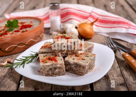 Pihtije - Serbian traditional dish. Cubes of aspic with pork meat on a plate. Selective focus. Stock Photo