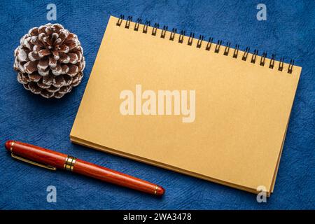 blank spiral notebook with a decorative frosty pine cone and luxury pen on art paper Stock Photo