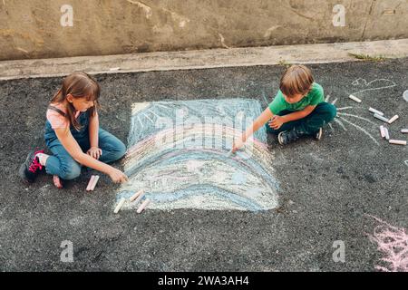 Two funny kids drawing with chalk, children playing together, top view Stock Photo