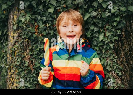 Outdoor portrait of funny little boy eating colorful ice cream, playing in the park Stock Photo