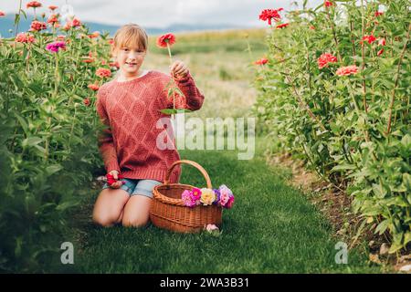 Pretty little girl working in autumn garden, child taking care of colorful chrysanthemum, gardener teenager enjoying warm and sunny day Stock Photo