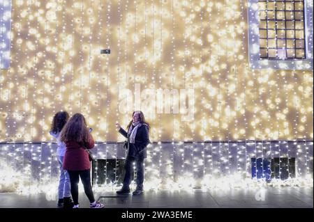 Rome, Italy. 1st Jan, 2024. A tourist takes a souvenir photo in front of a wall illuminated by a shower of Christmas lights in the New Year's Day in Rome. (Credit Image: © Marcello Valeri/ZUMA Press Wire) EDITORIAL USAGE ONLY! Not for Commercial USAGE! Stock Photo