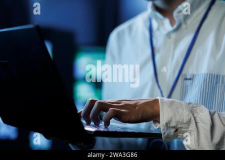 Man between server hub rows providing processing resources for businesses worldwide, blurry background. Scientist fixing data center mainframes tasked with managing massive databases, close up Stock Photo