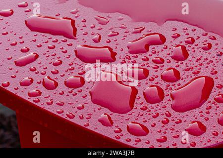 Water droplets on an impervious red surface Stock Photo