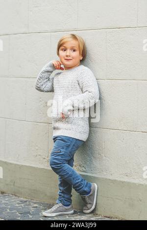 Outdoor portrait of cute 5-6 year old little boy, wearing grey knitted pullover Stock Photo