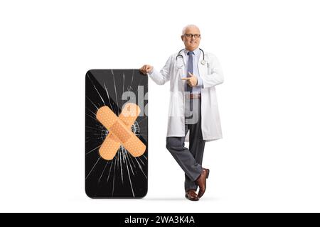 Doctor pointing at a broken screen on a smartphone fixed with a bandage isolated on white background Stock Photo