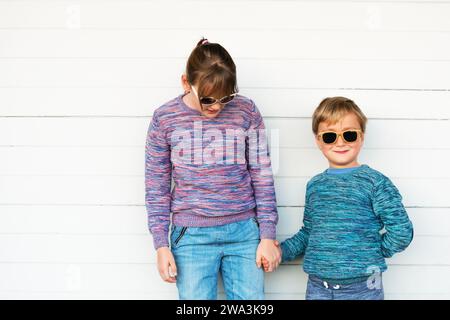 Fashion kids outdoors, wearing knitted pullovers and sunglasses Stock Photo