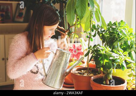 Little girl watering home plants in pots Stock Photo