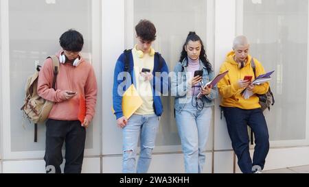 Four young diverse teenage students looking at smartphone on a campus Stock Photo