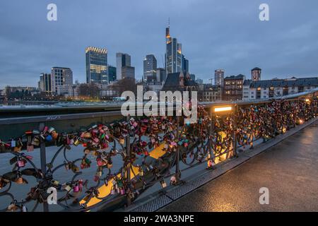 The pedestrian bridge, Iron Footbridge with love locks on the railing.sunset with a view of the skyline of the financial district of Frankfurt am Main Stock Photo