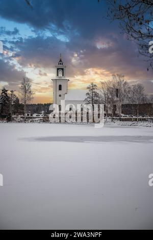 Small white church on a frozen lake in a cold winter landscape with snow and ice. Vårviks kyrka, Sweden, Europe Stock Photo