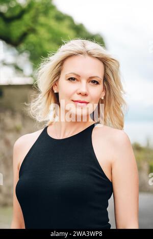 Outdoor portrait of young blond woman wearing black dress Stock Photo