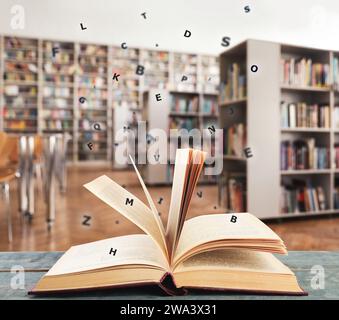 Open book with letters flying out of it in library Stock Photo