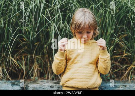 Outdoor fashion portrait of cute little boy wearing yellow hoody sweatshirt Stock Photo