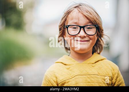 Close up portrait of adorable little kid boy wearing eyeglasses and yellow sweatshirt Stock Photo