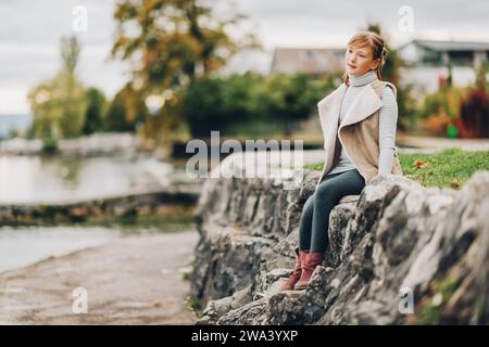 Outdoor portrait of pretty little girl resting by the lake on a cloudy day, image taken in Lausanne, Switzerland Stock Photo