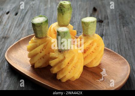 Peeled Small Pineapple or Ananas on Wooden Plate Stock Photo