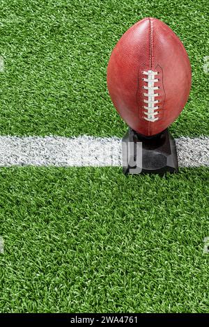 An American football on kicking tee with yard line Stock Photo