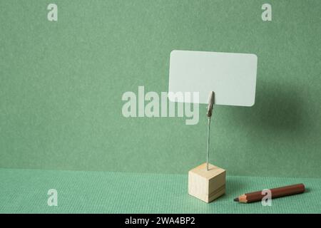 Memo pad with holder and colored pencil on desk. green wall background. copy space Stock Photo