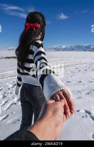 girl woman in a field with mountains in winter with snow on a sunny day. The concept of follow me on a journey Stock Photo