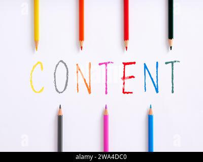 The handwritten word content and colorful crayons on white background. Rich content creation. Stock Photo